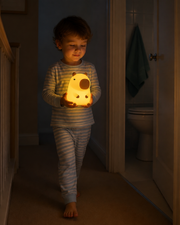Child carrying CapiZen capybara night light along a dim hallway – image 3
