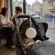 BabyCalm portable white noise machine on a pram during a rainy cafe outing